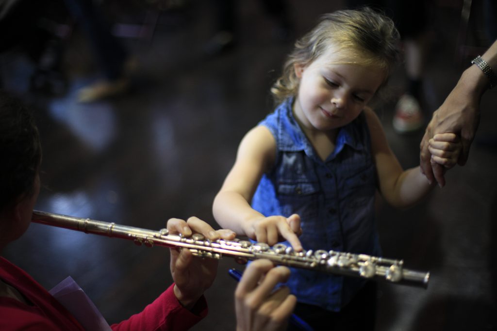 a young child curiously pressing the keys on a flute